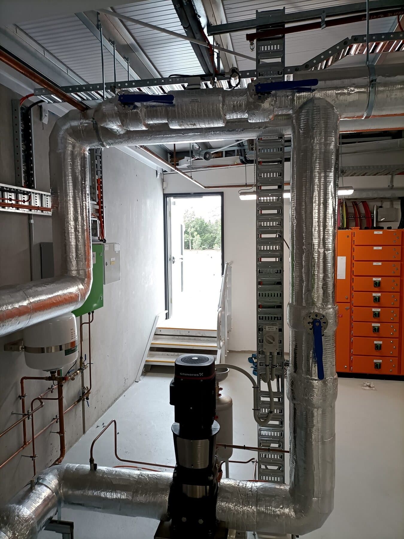 Mechanical services plant room — pumps, insulated pipework and switchboard